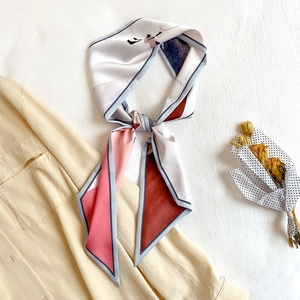 Détail d'un foulard en soie avec motifs géométriques roses et rouge rouille sur une chemise