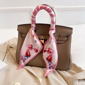 Detail of floral silk scarf tied on brown pebble leather handbag with gold padlock hardware