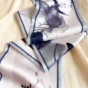 Détail d'un foulard étroit en soie avec imprimé floral sur fond de chemise en lin