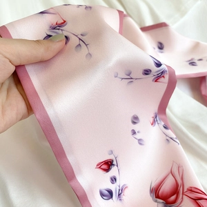 Detail of pink rose pattern floral silk scarf with glossy texture and stitched edges