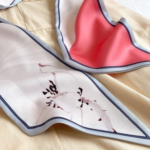 Gros plan d'un foulard en soie élégant avec imprimés floraux et touches de rouge corail