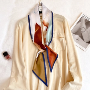 Écharpe étroite en soie imprimée multicolore nouée sur le col d'une chemise beige