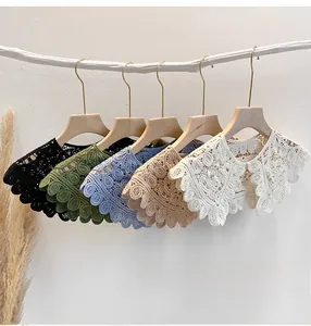 Detail of crochet floral lace shawls in five colors hanging on wooden hangers