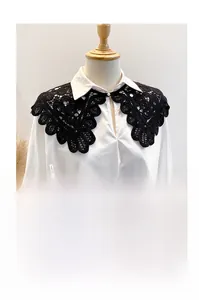 Detail of black hollow floral lace shawl featuring a white pearl button closure