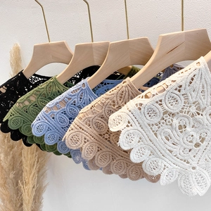 Detail of hollow lace shawls in five colors displayed elegantly on wooden hangers
