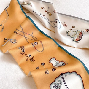 Macro detail of silk-like skinny scarf showing double-sided floral patterns and green stitching