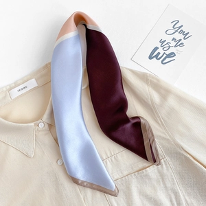Detail view of a color-block mulberry silk twilly scarf draped on a white shirt collar