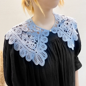Close-up of light blue hollow crochet lace shawl with a pearl button for women