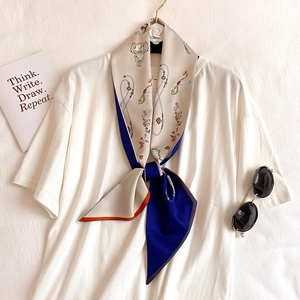 Detail of elegant floral and chain print silk scarf styled on a white neck top