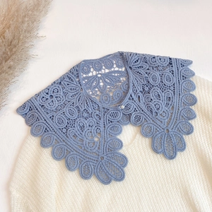 Detail of light blue hollow crochet lace collar with an elegant pearl button fastener