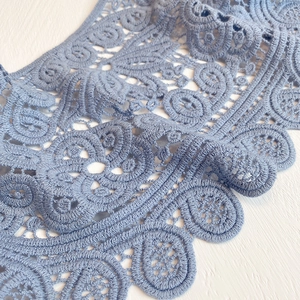 Detail of light blue crochet floral lace shawl with intricate hollow embroidery patterns