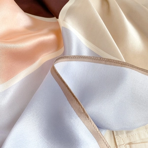 Close-up of geometric color block silk scarf showing premium satin texture and hem detail