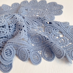 Macro view of blue floral hollow lace embroidery with scallop edges on cotton fabric