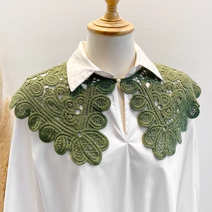 Green hollow lace crochet shawl with floral embroidery and pearl button on white shirt