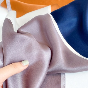 Macro view showing the smooth silk satin texture and color block design of the scarf