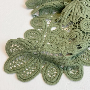 Macro shot of olive green hollow crochet floral patterns and lace texture details