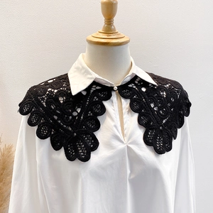Detail view of a black hollow lace collar with floral patterns and a pearl button