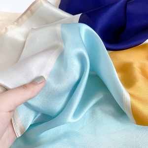 Close-up of premium silk scarf showing smooth texture and color-block design in sunlight