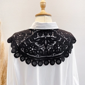 Detail of black hollow-out crochet lace shawl accessory on a white shirt collar