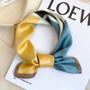 Detailed close-up of premium silk scarf with elegant geometric color-block pattern