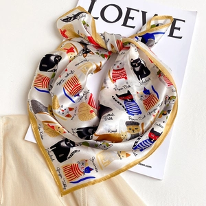 Detailed flat lay of silk scarf showing artistic cat illustrations and hand-rolled edges