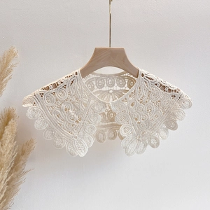 Detail of hollow lace shawl with floral embroidery and a small pearl buckle closure