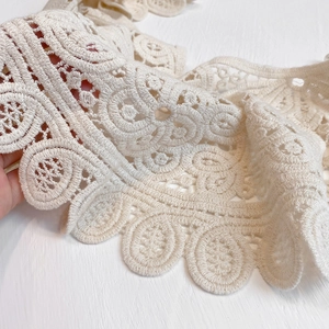 Detailed macro shot of hollow lace embroidery and scalloped edges on a beige shawl