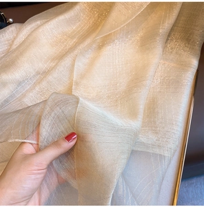 Detail of silk-blend champagne gold scarf with metallic thread and subtle plaid texture