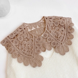 Detail of hollow lace shawl with brown crochet patterns and a white pearl button