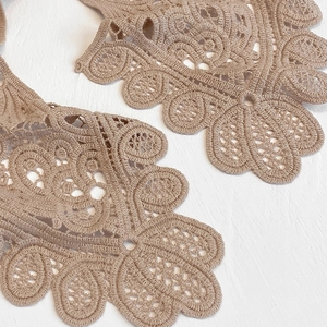 Macro shot of exquisite beige floral lace embroidery detailing on a hollow shawl collar