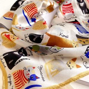 Detail of silk scarf with hand-drawn cat illustrations and high-quality fabric texture