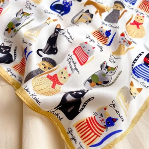 Detailed view of silk scarf featuring hand-drawn cat illustrations and yellow stitching
