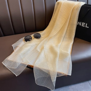 Detailed texture of champagne gold silk shawl with metallic lurex threads on leather