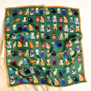 Detailed pattern of silk scarf showing artistic cat illustrations and golden edges