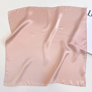 Detail of pink silk square scarf with satin finish and neat hemmed edges on white background