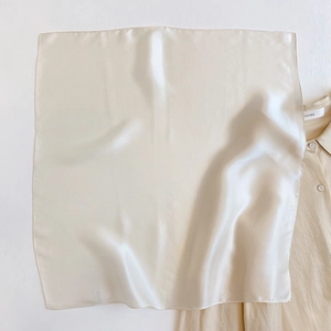 Detail of a creamy white pure silk square scarf with satin luster and fine rolled edges