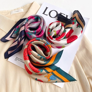 Close-up of silk scarf featuring strawberry prints and contrasting striped edge details