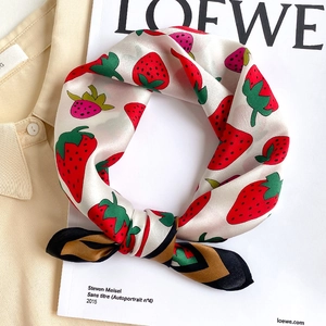 Detail of silk scarf tied in a bow featuring a vibrant red strawberry print with borders
