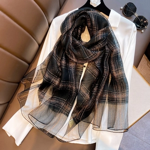 Detail of silk blend scarf featuring metallic gold thread plaid on black fabric