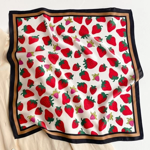 Close-up of a silk square scarf with strawberry print and striped border on a shirt