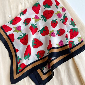Close-up of strawberry print silk square scarf on shirt with elegant striped hem detailing