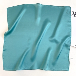 Detail of teal silk square scarf showing smooth texture and refined stitched edges