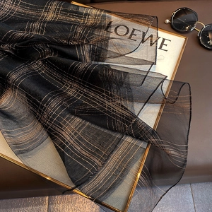 Detail of sheer black silk blend fabric with golden metallic thread plaid texture