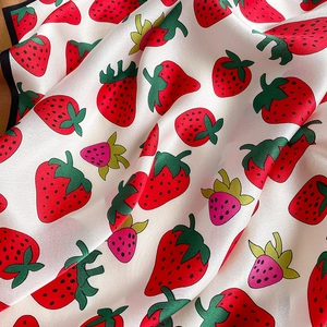 Detail of silk scarf showing vibrant strawberry patterns and smooth satin texture