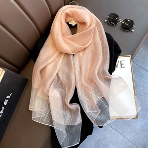 Detail of light pink silk blend scarf with golden metallic thread on a display stand