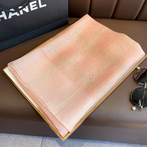 Detail showing peach pink silk scarf with silver metallic grid texture in luxury tray