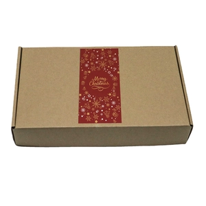 Brown kraft gift box with red Merry Christmas adhesive label and gold holiday graphics