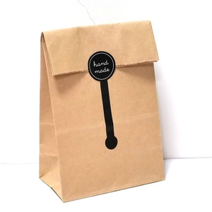 Dettaglio dell'adesivo nero 'Hand Made' su un sacchetto regalo in carta kraft marrone