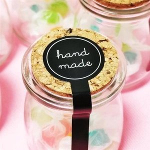 Dettaglio del sigillo nero 'Hand Made' su un vaso di vetro con tappo di sughero