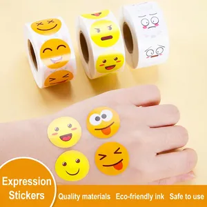 Three rolls of waterproof emoji reward stickers for kids shown on hand for size